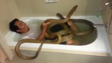 Il prend son bain avec deux serpents!